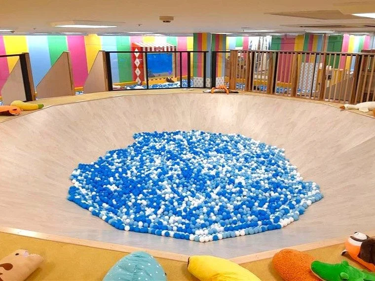 青と白のボールで満たされた大きなボールプールがある室内遊び場の様子