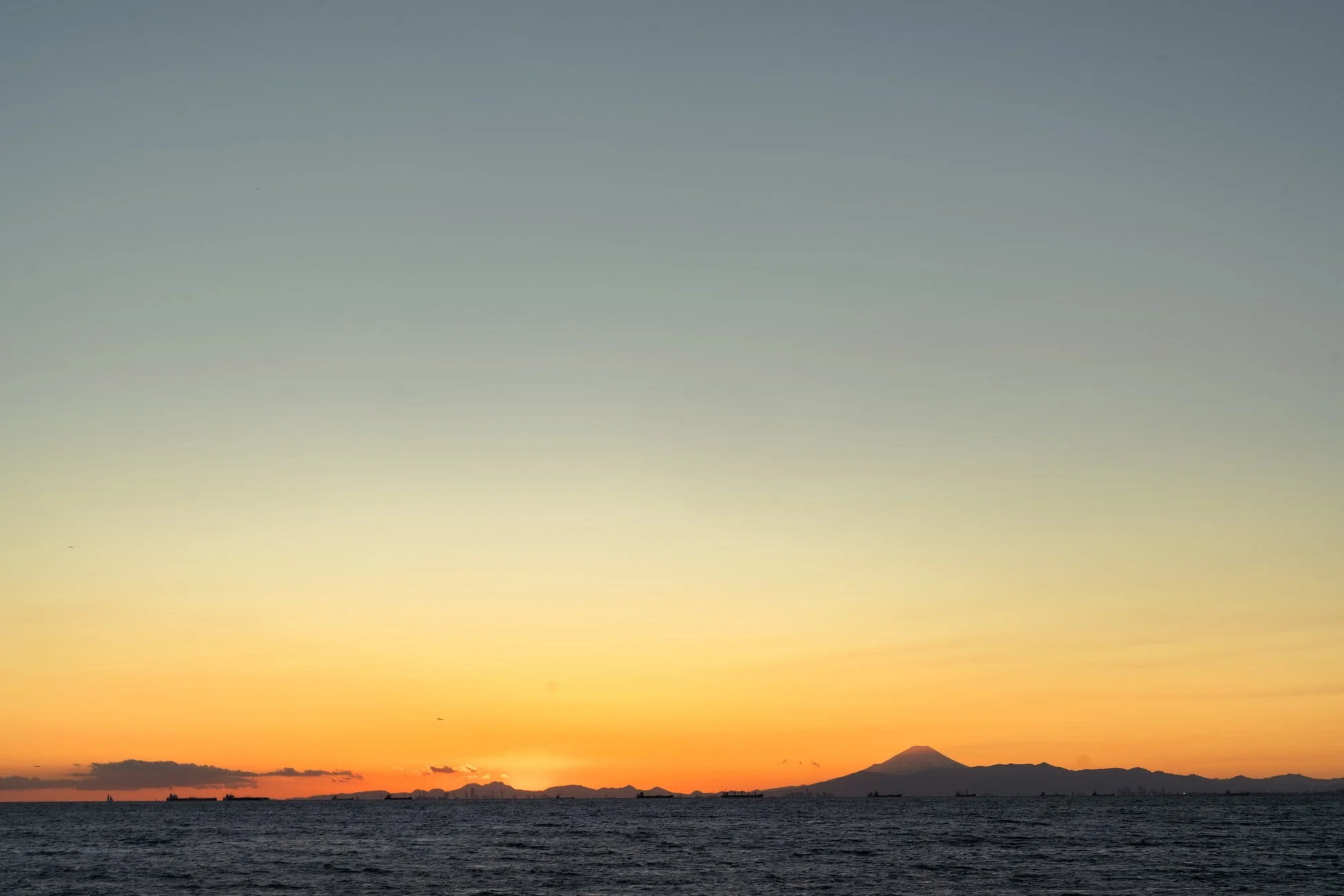 夕焼けに染まる広大な空と海、地平線には雄大な富士山