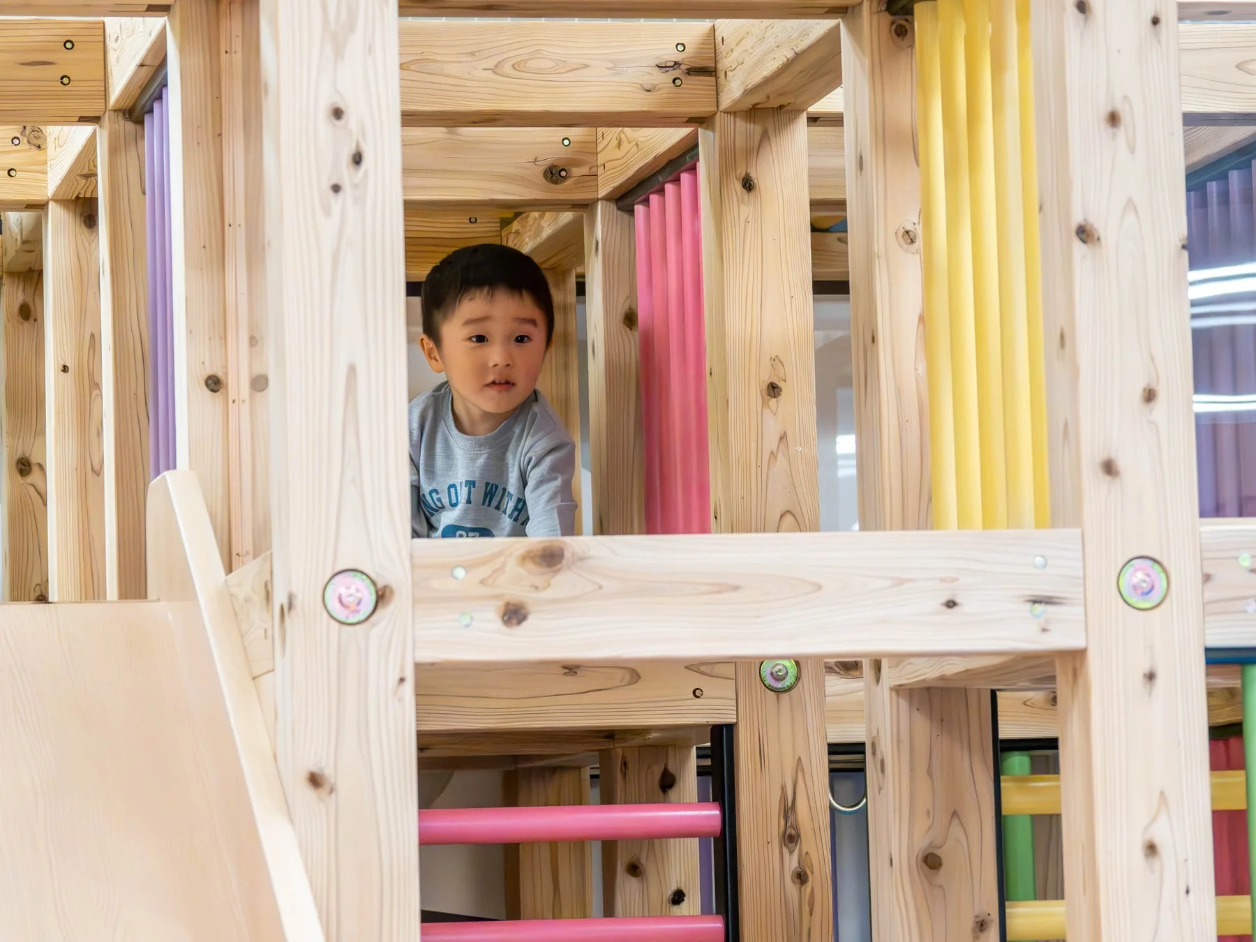 木製の室内遊具で遊ぶ幼い男の子