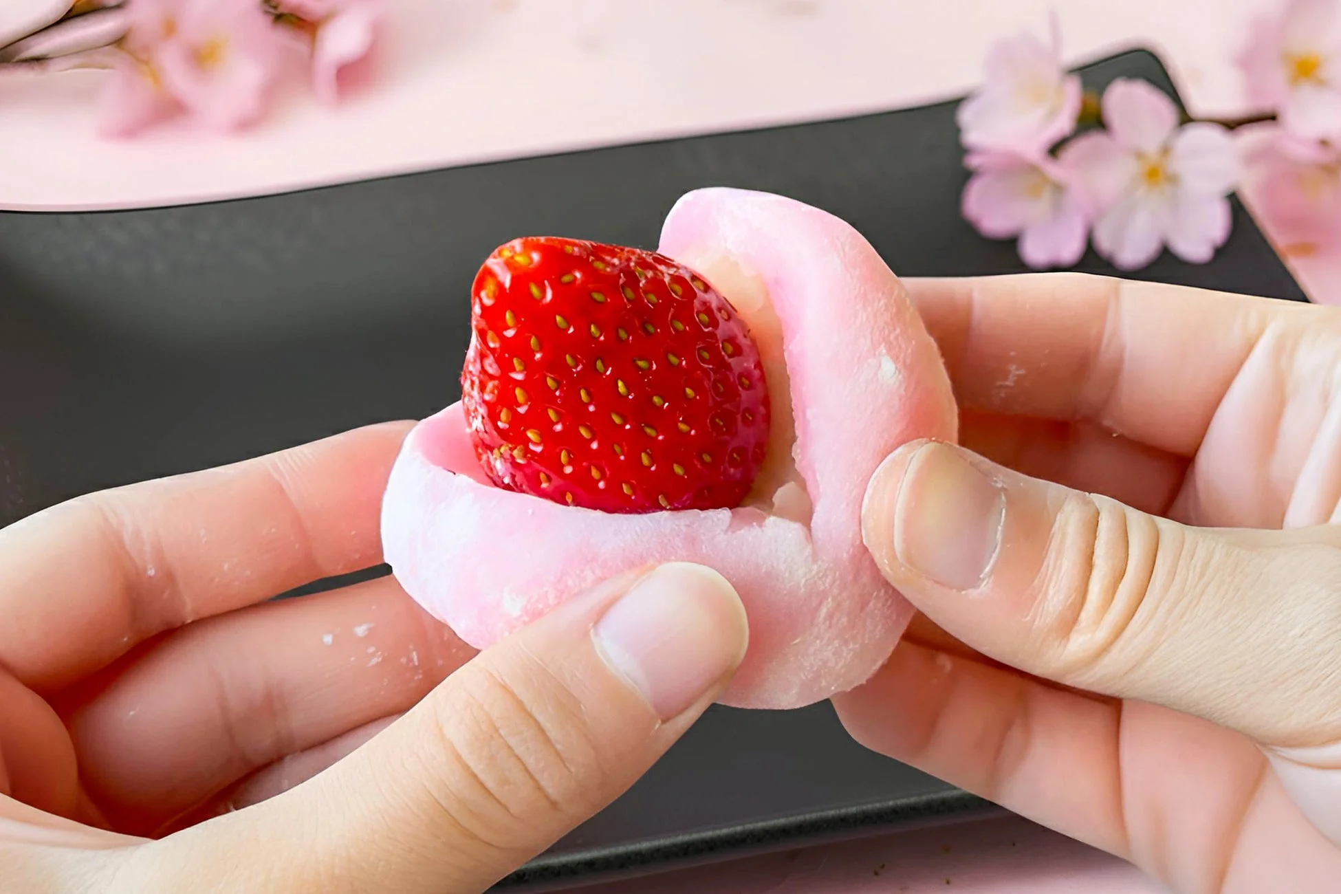 手でピンクのいちご大福が持たれた断面