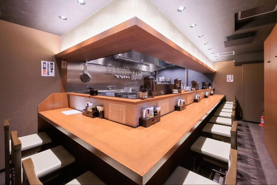 清潔感のあるラーメン店のカウンター席と厨房の様子