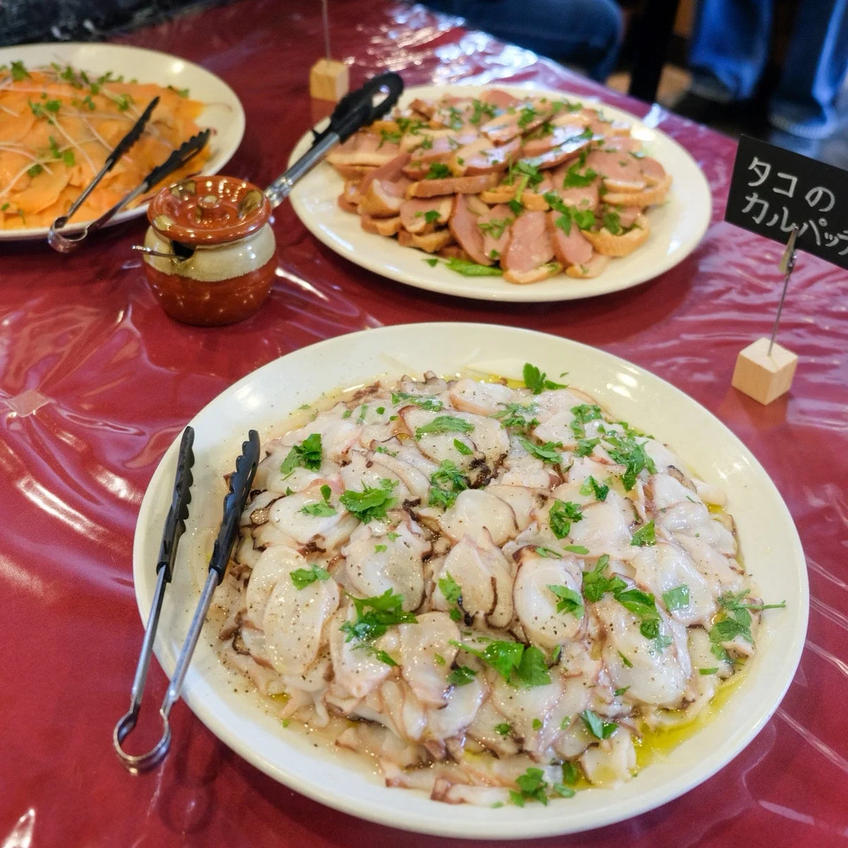 タコのカルパッチョ、鴨肉のスライスなどが並べられたビュッフェ形式の食卓