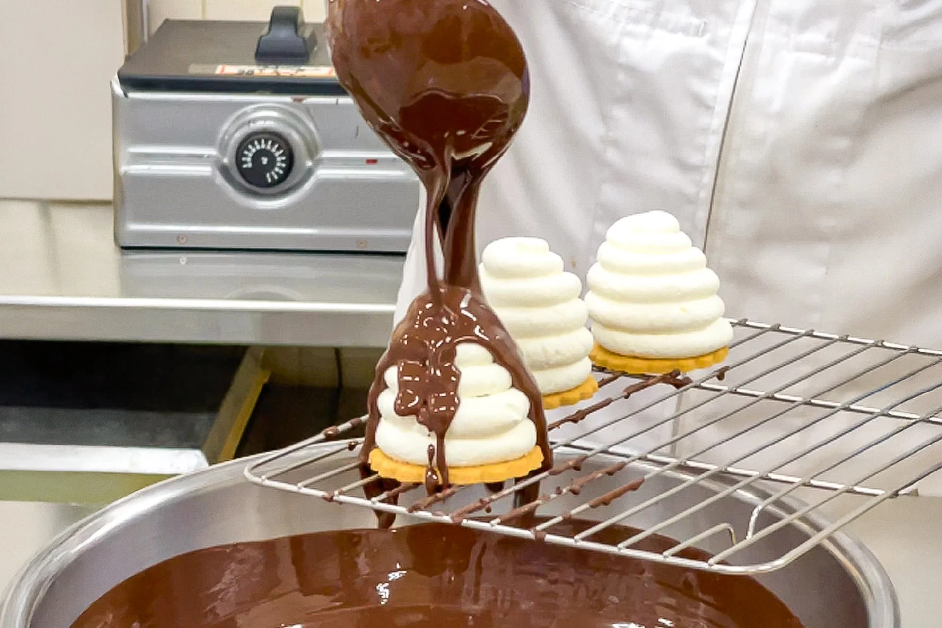 白いクリーム状のデザートに溶けたチョコレートをかける様子