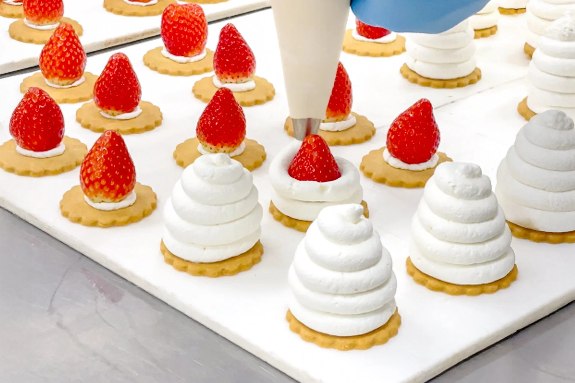 クッキーにイチゴとホイップクリームを飾り付ける様子