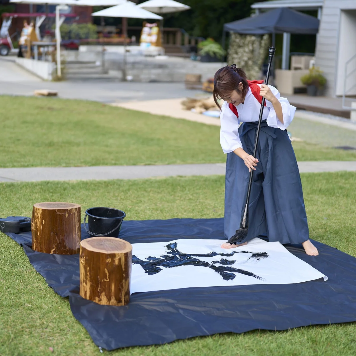 屋外で書道パフォーマンスを行う女性