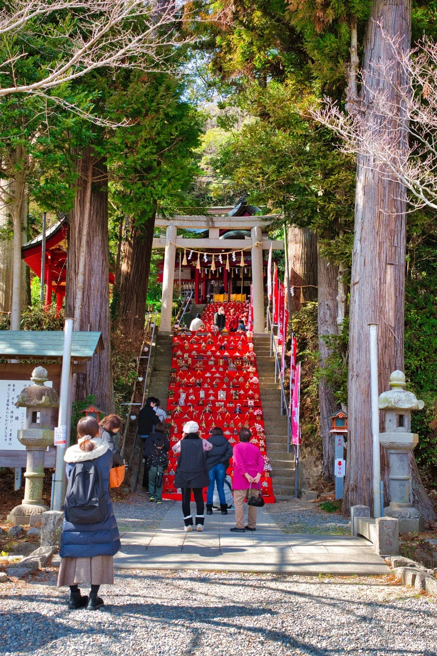神社の階段に飾られたひな人形と訪れる人々