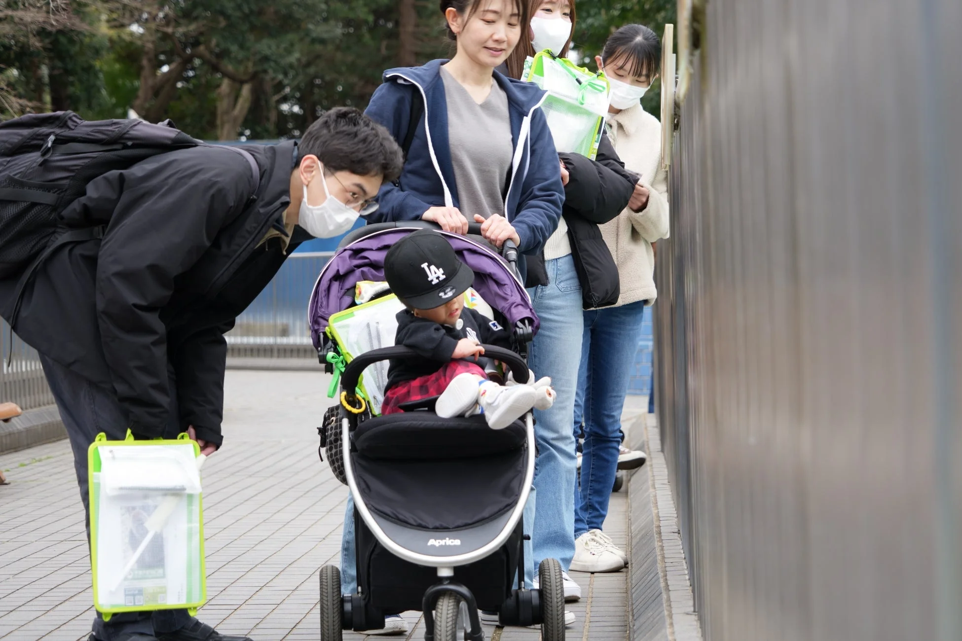 ベビーカーと赤ちゃんを囲んで屋外で交流する人々