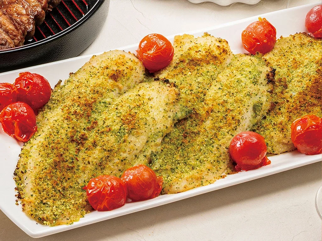 白い皿にハーブをまぶして焼かれた魚のフィレ